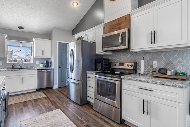 kitchen featuring sink, white cabinetry, vaulted ceiling, hanging light fixtures, and appliances with stainless steel finishes