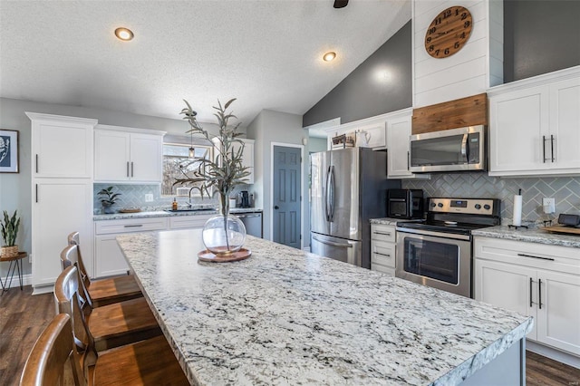 kitchen featuring white cabinetry, appliances with stainless steel finishes, dark hardwood / wood-style floors, and a center island