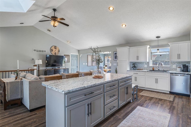 kitchen with hanging light fixtures, a kitchen island, stainless steel dishwasher, and white cabinets