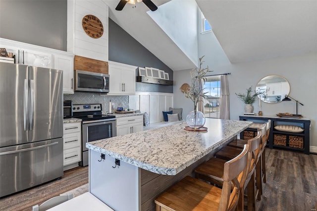 kitchen featuring white cabinetry, dark hardwood / wood-style flooring, a kitchen breakfast bar, a center island, and stainless steel appliances