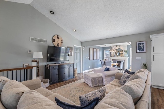 living room featuring lofted ceiling, a notable chandelier, dark hardwood / wood-style floors, and a textured ceiling