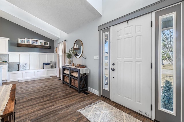 entryway featuring lofted ceiling, dark hardwood / wood-style flooring, and a textured ceiling