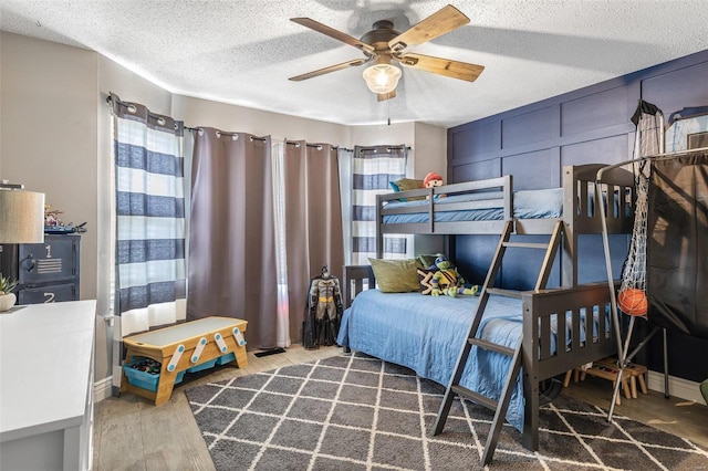 bedroom with ceiling fan, hardwood / wood-style floors, and a textured ceiling