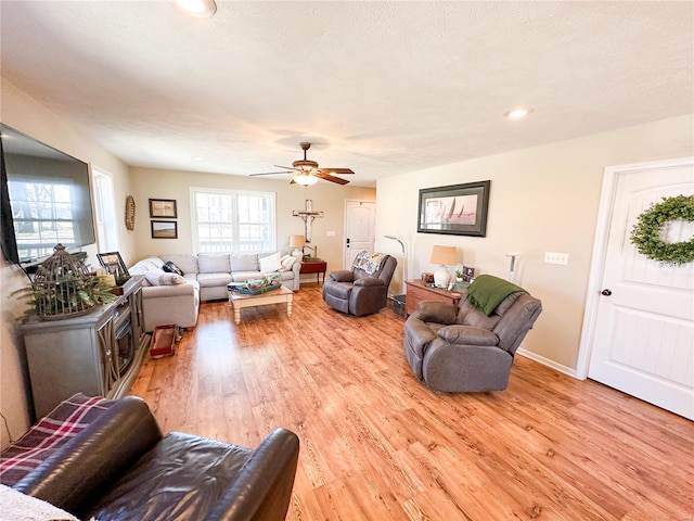 living room with ceiling fan, a textured ceiling, and light wood-type flooring