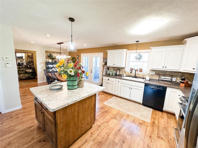 kitchen with sink, dishwasher, white cabinetry, a kitchen island, and decorative light fixtures