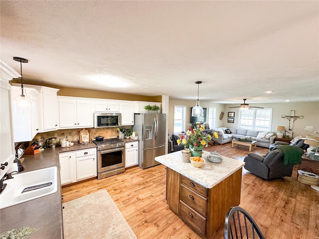 kitchen with hanging light fixtures, white cabinets, and appliances with stainless steel finishes