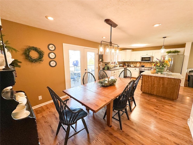 dining room featuring french doors, a textured ceiling, and light wood-type flooring