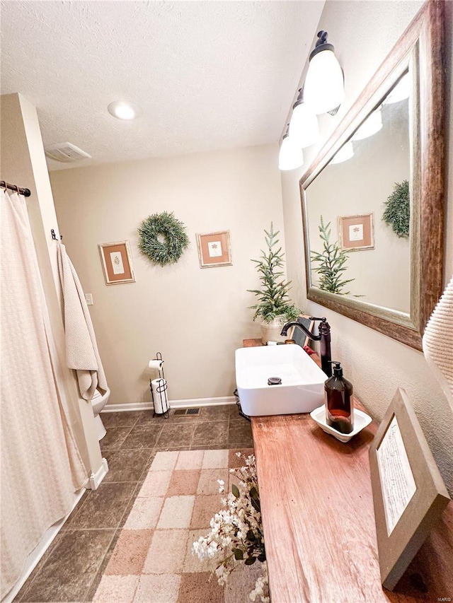 bathroom with sink, a textured ceiling, and toilet