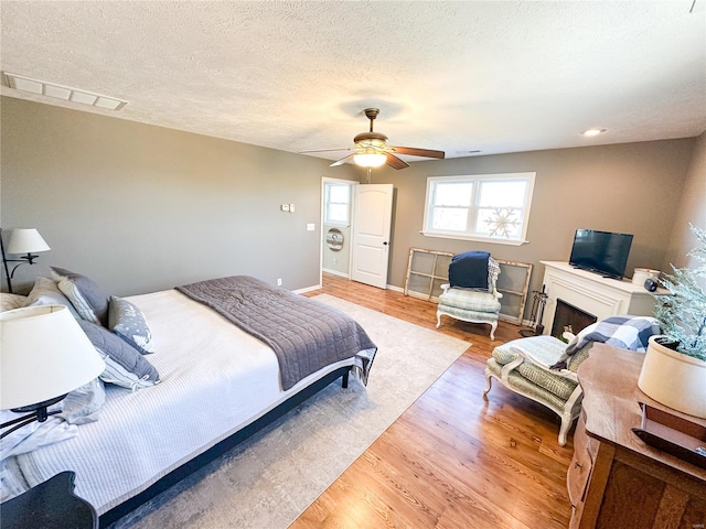 bedroom featuring ceiling fan, a textured ceiling, and light wood-type flooring