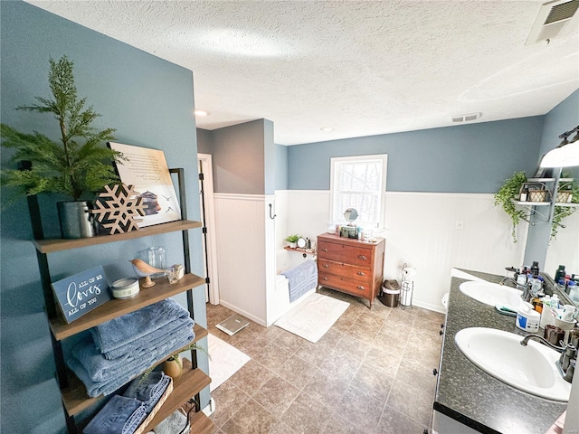 bathroom featuring a bathing tub, vanity, and a textured ceiling