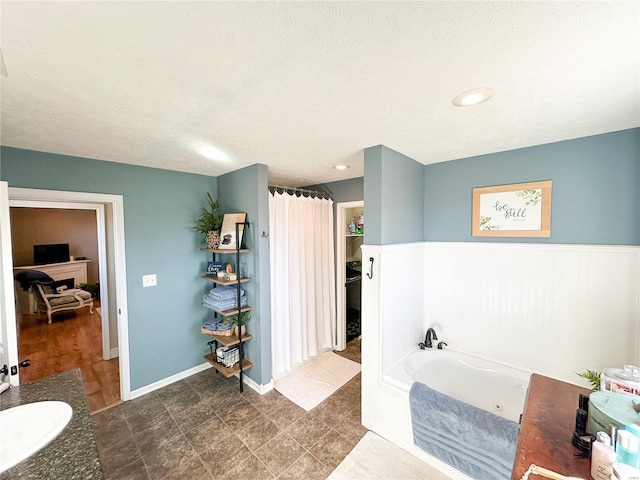 bathroom featuring vanity, a textured ceiling, and a tub