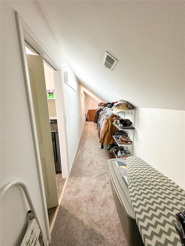 hall with lofted ceiling, light colored carpet, and a textured ceiling