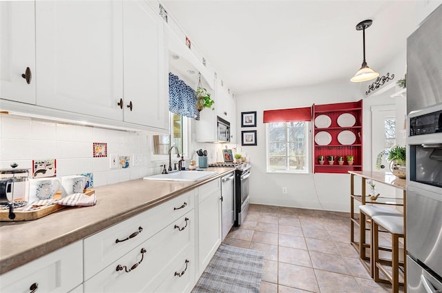 kitchen featuring sink, white cabinetry, plenty of natural light, stainless steel appliances, and decorative light fixtures