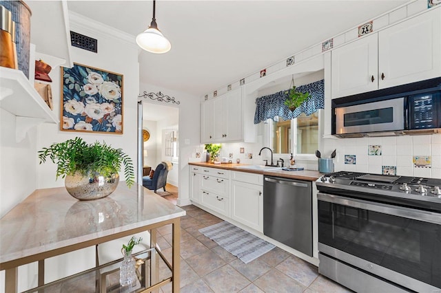 kitchen featuring stainless steel appliances, white cabinetry, sink, and decorative light fixtures