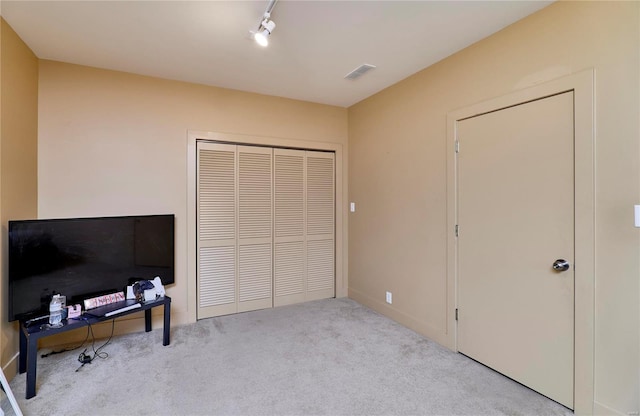 carpeted bedroom featuring track lighting and a closet