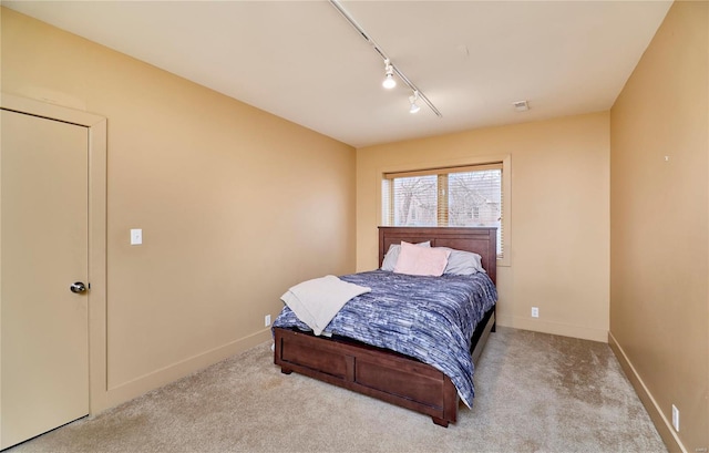 bedroom with rail lighting and light colored carpet