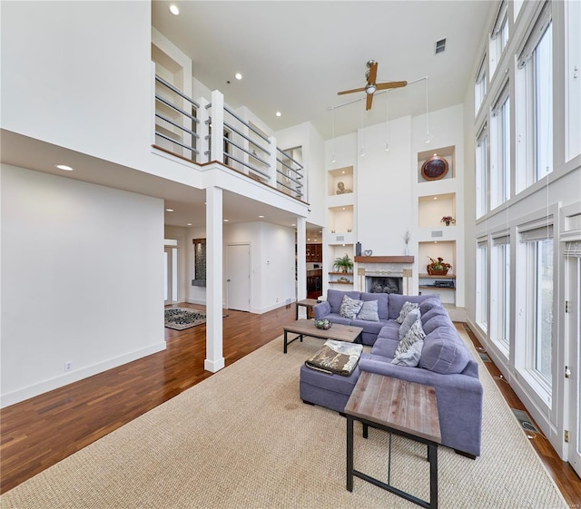 living room featuring hardwood / wood-style flooring, a towering ceiling, and built in features