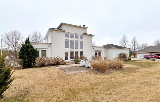 rear view of house featuring a yard, a patio, and a garage