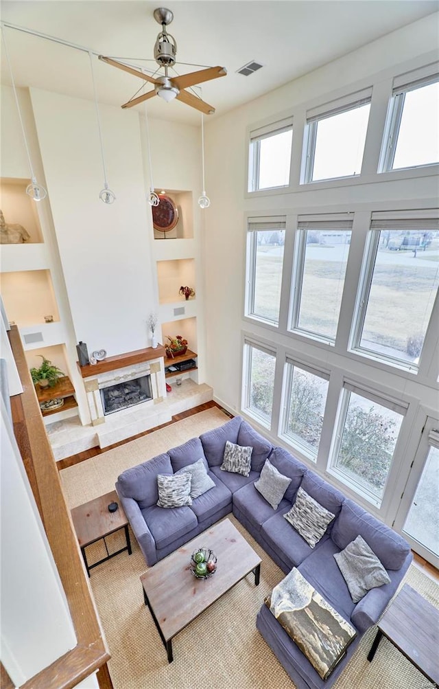 living room with plenty of natural light, a fireplace, built in features, and a high ceiling