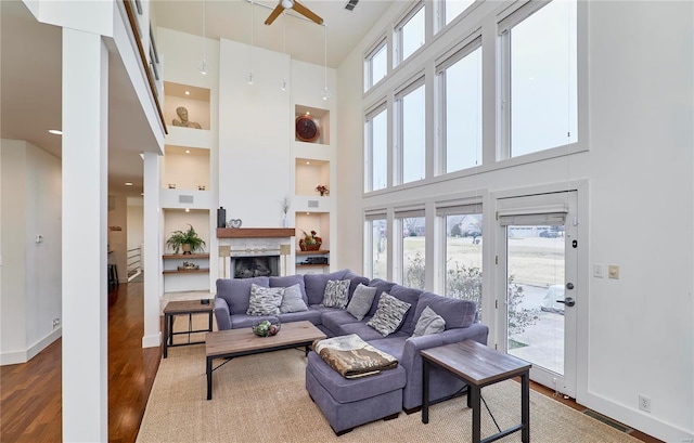 living room featuring hardwood / wood-style flooring, plenty of natural light, built in shelves, and a towering ceiling