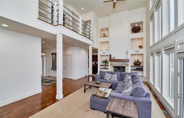 living room with hardwood / wood-style flooring, a towering ceiling, built in features, and a wealth of natural light