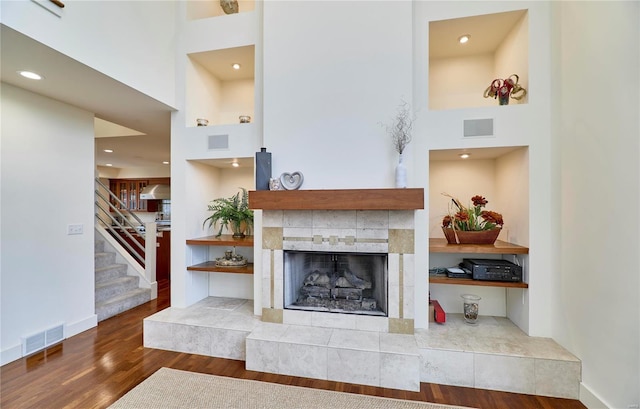 living room with hardwood / wood-style floors, a tile fireplace, and a high ceiling