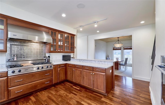 kitchen featuring wall chimney exhaust hood, stainless steel gas cooktop, dark hardwood / wood-style flooring, kitchen peninsula, and pendant lighting