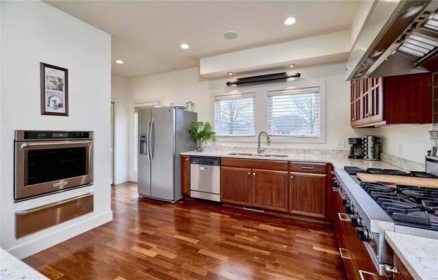 kitchen featuring extractor fan, appliances with stainless steel finishes, sink, dark hardwood / wood-style flooring, and light stone counters