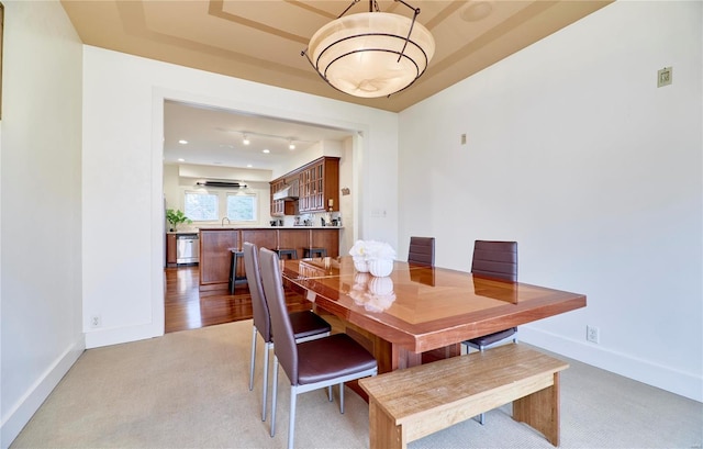 carpeted dining room featuring sink and a tray ceiling