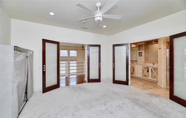 unfurnished bedroom featuring light carpet, french doors, and ceiling fan