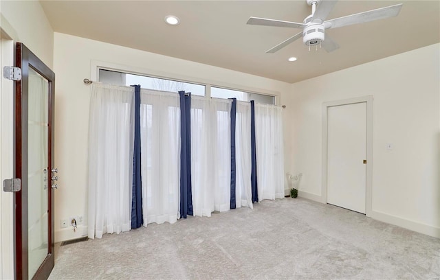 empty room featuring ceiling fan and light colored carpet