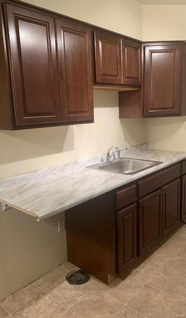 kitchen featuring sink, dark brown cabinetry, and light tile patterned floors