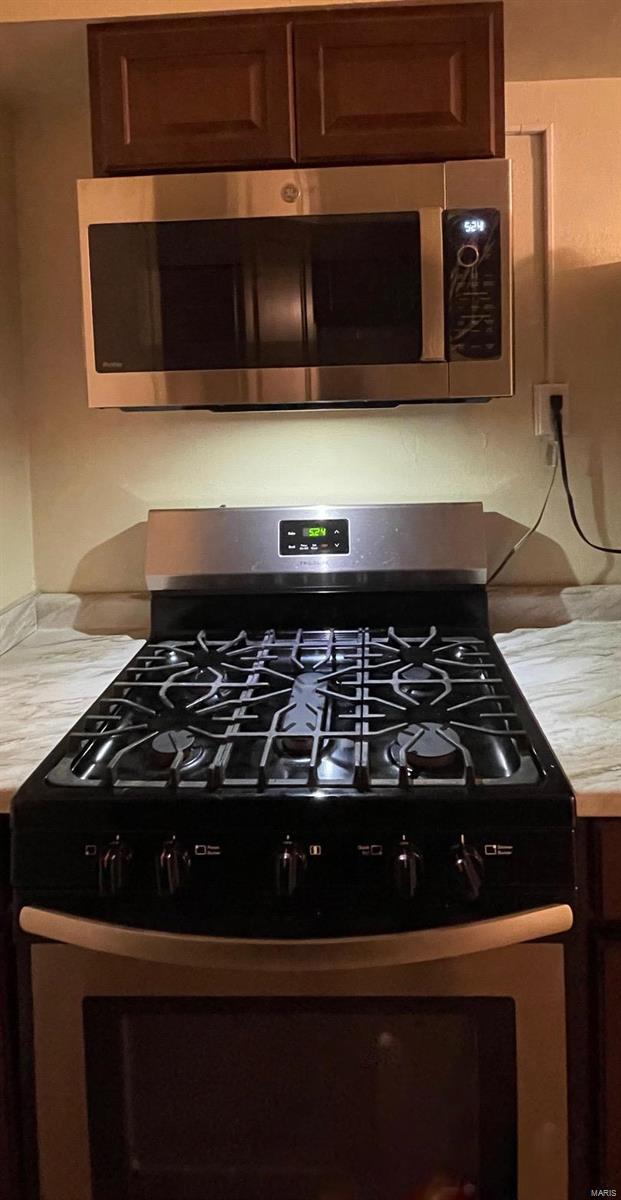 room details with dark brown cabinets, butcher block countertops, and stainless steel appliances