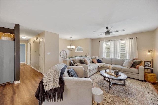 living room with hardwood / wood-style flooring and ceiling fan with notable chandelier