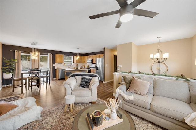 living room featuring ceiling fan with notable chandelier, sink, and hardwood / wood-style floors