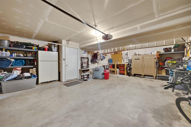 garage with a garage door opener, white fridge, and a workshop area