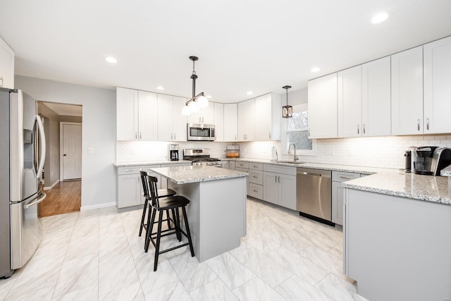 kitchen with stainless steel appliances, white cabinetry, a kitchen island, and decorative light fixtures