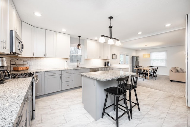 kitchen featuring appliances with stainless steel finishes, decorative light fixtures, sink, white cabinets, and light stone counters