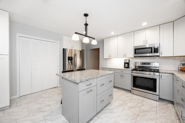 kitchen featuring appliances with stainless steel finishes, pendant lighting, gray cabinetry, decorative backsplash, and a center island