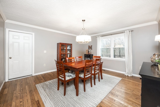 dining space featuring hardwood / wood-style flooring, ornamental molding, and a textured ceiling