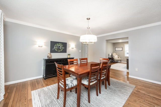 dining area featuring a notable chandelier, crown molding, wood-type flooring, and a textured ceiling