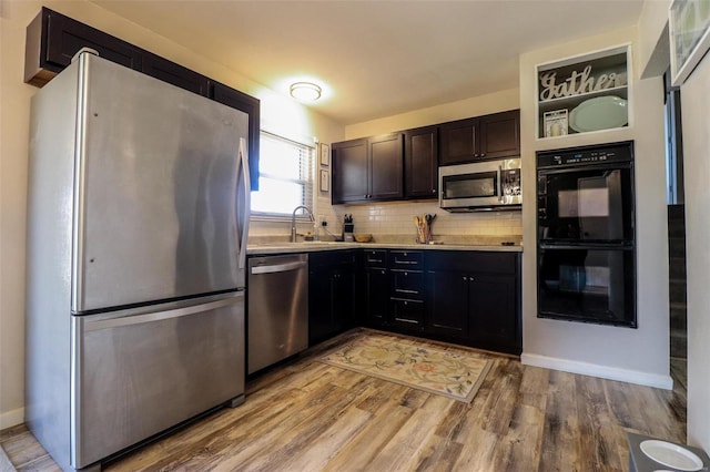 kitchen featuring stainless steel appliances, sink, light hardwood / wood-style floors, and backsplash