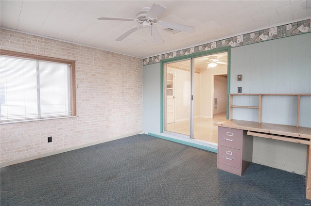 unfurnished office featuring ceiling fan, brick wall, and dark carpet