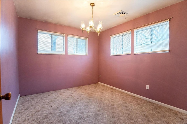 carpeted spare room with a notable chandelier