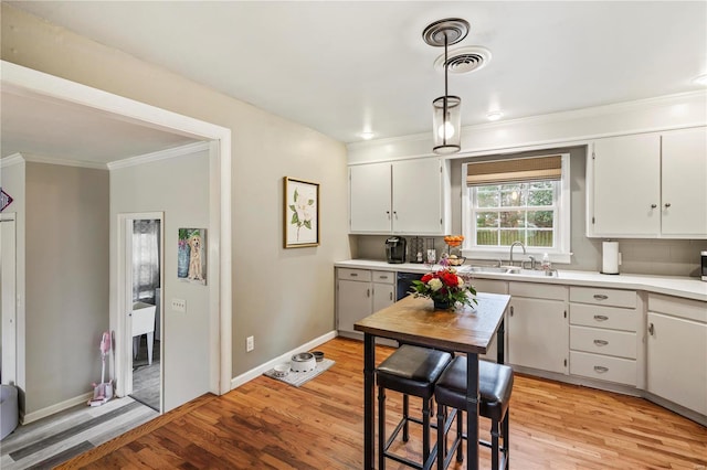 kitchen featuring hanging light fixtures, sink, white cabinets, and light hardwood / wood-style floors