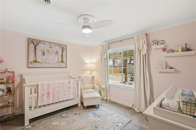 bedroom featuring ornamental molding, a nursery area, ceiling fan, and carpet