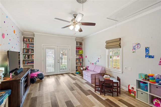 rec room featuring french doors, ceiling fan, ornamental molding, and light wood-type flooring