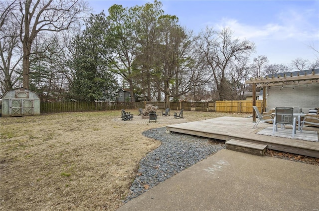 view of yard featuring a wooden deck, a pergola, a shed, and an outdoor fire pit