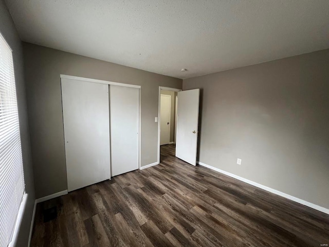 unfurnished bedroom with dark hardwood / wood-style floors, a textured ceiling, and a closet