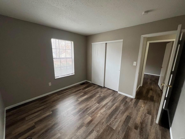 unfurnished bedroom featuring a textured ceiling, dark hardwood / wood-style flooring, and a closet